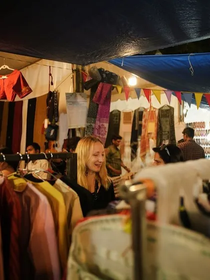 A shopper browses through a rack of handmade apparel. Our markets offer a chance to find unique clothing directly from the creators.