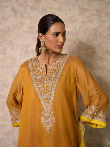 A close-up of a mustard yellow kurta with exquisite silver embroidery around the neckline. The craftsmanship is designed to draw the eye and highlight your features.