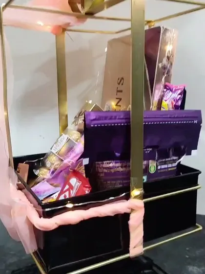 A slightly different angle of the metal bow hamper, showing the careful arrangement of each chocolate bar and box.