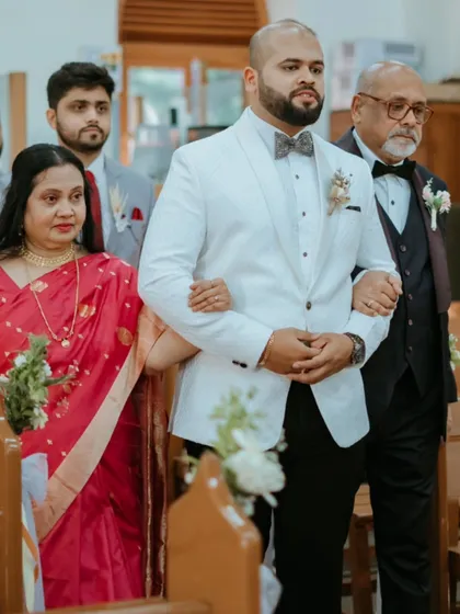 The groom's proud walk down the aisle with his parents, a significant moment at the start of the Catholic wedding ceremony.