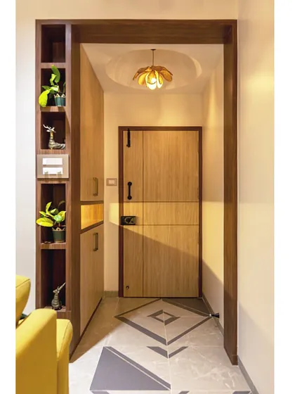 The entryway to this home features custom flooring, a sleek shoe cabinet with integrated shelving for decor, and a warm, welcoming ambiance.