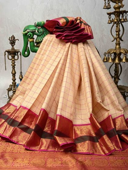 A classic checkered Kanjivaram silk saree in cream with a deep red and black border. This timeless design is a staple in any South Indian silk collection.