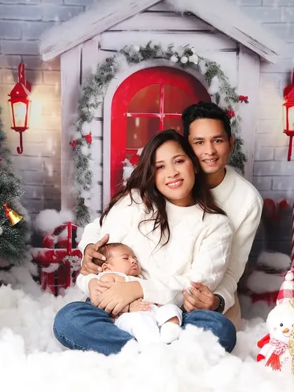 The family smiles for a classic portrait in their matching white sweaters and Santa hats.
