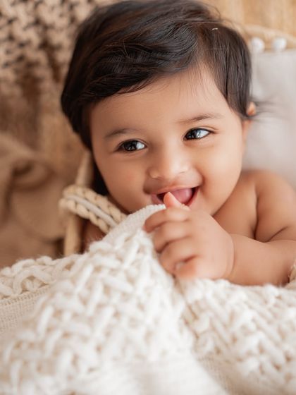 A baby girl chewing on a soft blanket.
