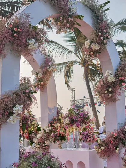 The floral-adorned arches of the entranceway, with palm trees peeking through. This shows how I integrate the natural surroundings into my destination wedding designs.