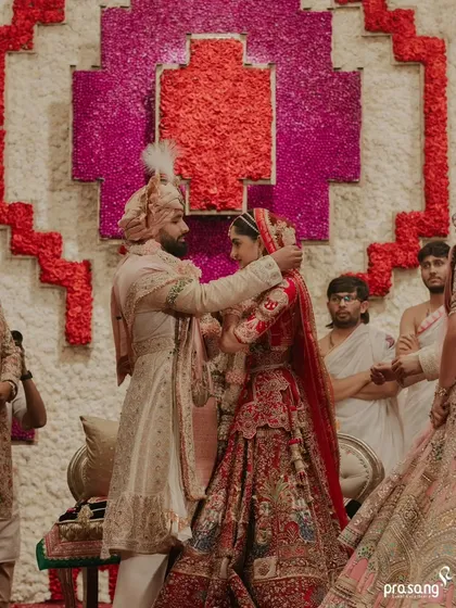 The groom lovingly places the sindoor, a pivotal moment in the ceremony. The backdrop of intricate floral art frames this intimate ritual beautifully.