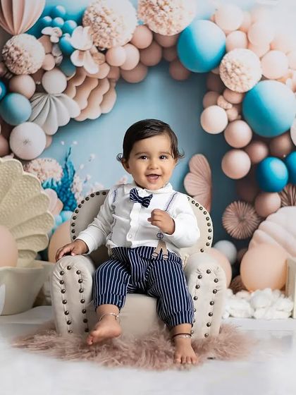 A handsome little man celebrating his first birthday. We provide a variety of outfits, like this bow tie and suspenders, for your baby's big day.