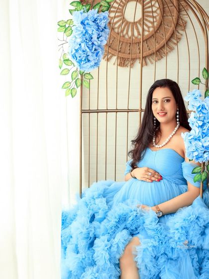 A serene portrait of the mom-to-be seated in our golden birdcage chair. The soft lighting and floral accents create a peaceful and elegant atmosphere.