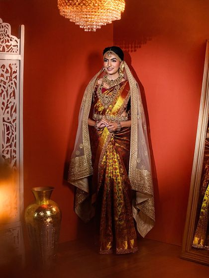 A full-length shot of a bride in a magnificent saree, standing in a beautifully decorated corner of the studio. This shows how we utilize our space and props to create a complete scene.