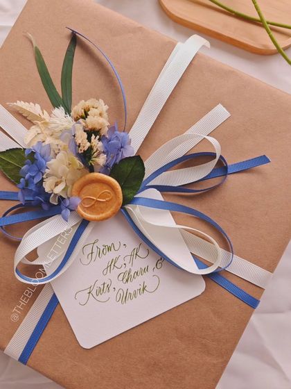 A beautifully wrapped wedding gift featuring engraved initials for the newlywed couple. The gift tag is also handwritten, completing the personalized experience.