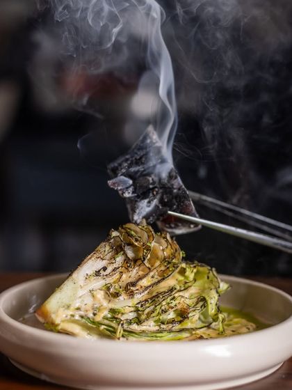 The smoke from the hot charcoal infuses the Manor Caesar salad, creating a memorable dining experience.