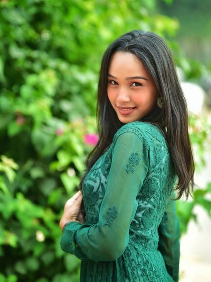 A sweet, over the shoulder smile. This pose is flattering and engaging, and the green background makes her stand out beautifully.