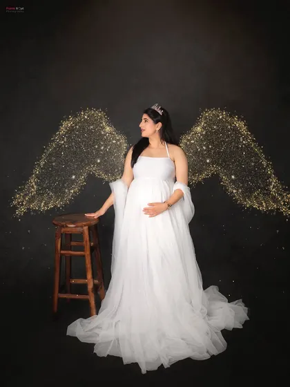 For the momma who wants a touch of magic. This angelic portrait features a beautiful mom-to-be in a classic white gown, adorned with sparkling light wings for a truly heavenly maternity photo.