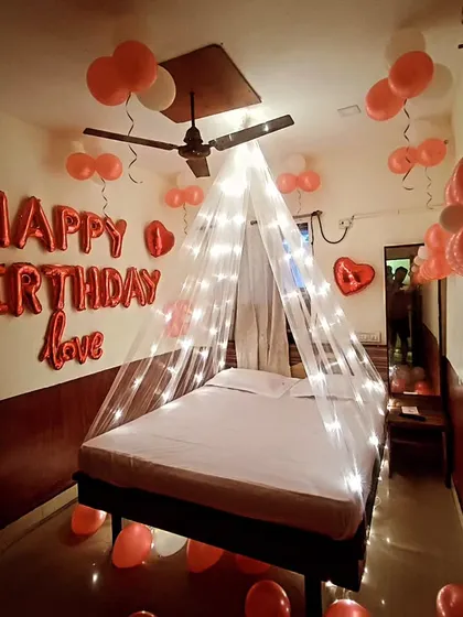 A classic red and white themed birthday room decoration. This setup includes "Happy Birthday love" foil balloons on the wall and a light-up canopy over the bed for a cozy and celebratory feel.