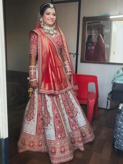 A full-length shot of the bride, showcasing her entire stunning red and white lehenga.