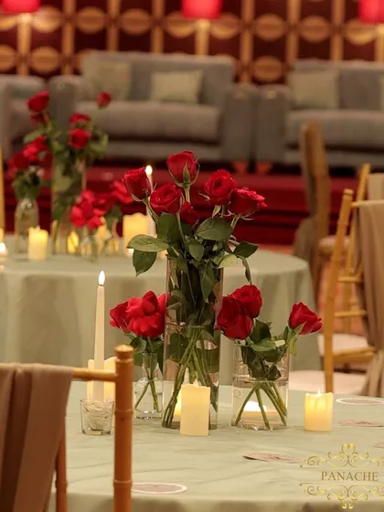 A centerpiece of red roses and candles on a guest table, adding a touch of romance to the modern setup.