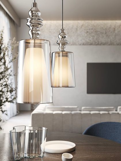 Two Alibaglass pendants provide warm, focused light over a dining table, their transparent forms beautifully complementing the glassware on the table.