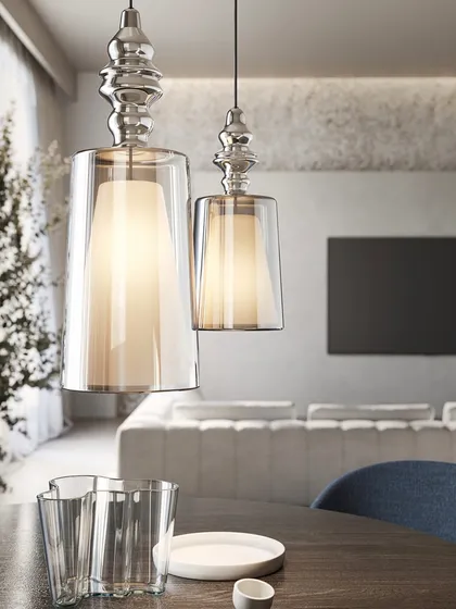 A pair of these reimagined glass pendants over a dining table. The design features an inner diffuser, which creates a soft, warm glow, while the outer clear glass adds depth and reflection.