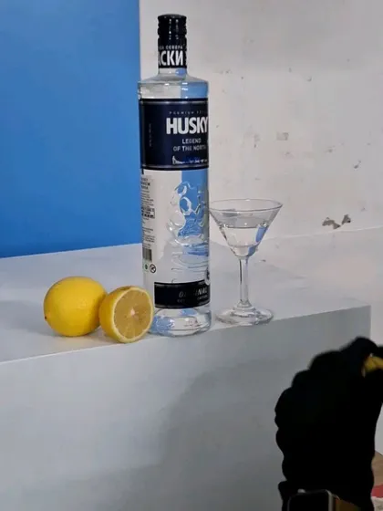 Another angle of the vodka setup, showing the arrangement of the bottle, glass, and fresh lemons.