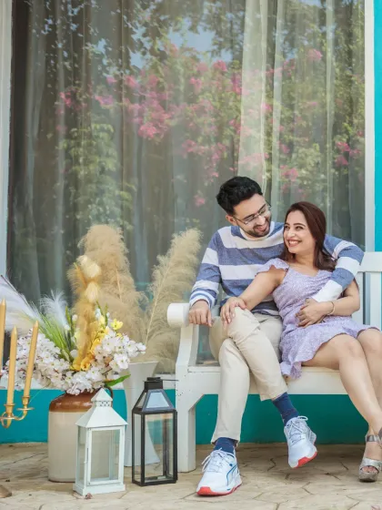 A relaxed and happy moment on a white bench. The couple's casual outfits and the bright, cheerful setting make for a lovely and natural portrait.
