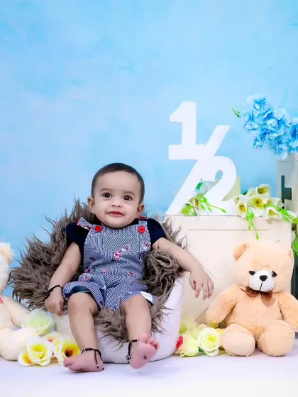 A full view of the half-birthday setup, showing the baby boy surrounded by teddy bears and flowers.