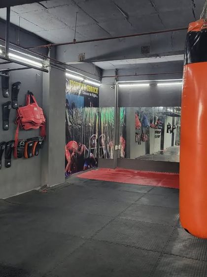 The "Fighting Choice" heavy bag hanging ready for the next session, with our wall of protective gear in the background. We provide everything you need to train hard and safe.