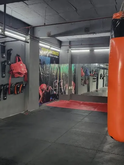The "Fighting Choice" heavy bag, a core piece of equipment for our striking training. Behind it, you can see our wall-mounted gear storage, keeping the gym organized and professional.