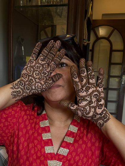 A happy client showing off her fully covered palms. This dense, fine-lined floral pattern is a classic choice for any celebration.