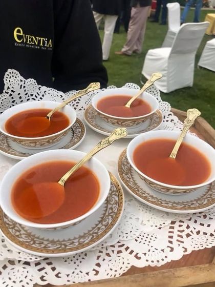 Warm tomato soup served in elegant porcelain bowls with golden spoons. Even the simplest dishes are presented with care to enhance the dining experience.