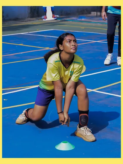 This player is in a low defensive stance, ready to dig a tough spike. Agility and a low center of gravity are key to a strong defense.