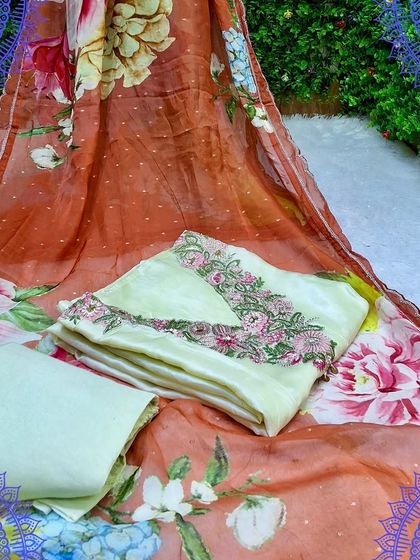 An elegant unstitched suit set with a digitally printed organza dupatta. The off-white top has delicate floral embroidery that complements the dupatta perfectly.