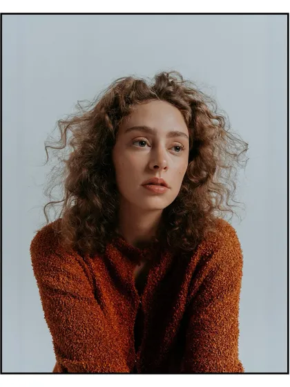 A soft, natural light portrait of a model with curly hair, featured in Flanelle Magazine. The focus is on capturing a quiet, contemplative expression, ideal for a model's portfolio or a beauty editorial.