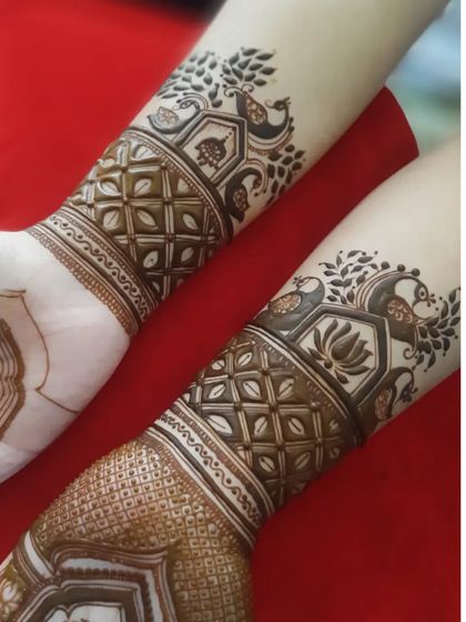 A detailed look at the wrist and forearm portion of an engagement mehendi. This design features peacock motifs and intricate geometric bands.