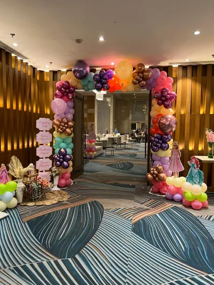 A colorful balloon arch at the entrance of a princess party, with cutouts of different Disney princesses welcoming the guests.