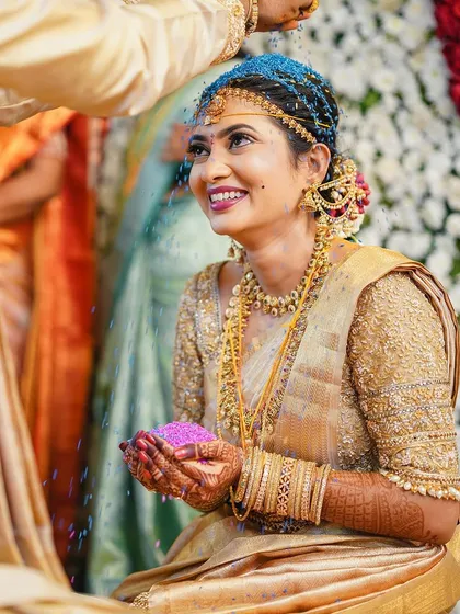 The vibrant colors of the ceremony complement Rakshita's stunning gold saree and traditional makeup.