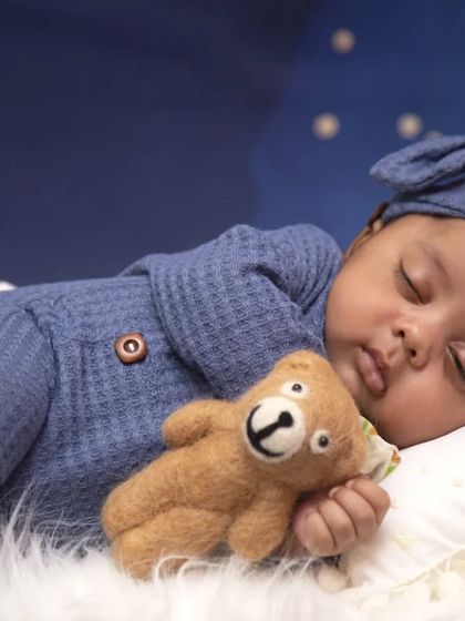 A close-up shot focusing on the baby's serene expression while sleeping. The soft textures of the bedding and the gentle lighting create a warm and comforting atmosphere.
