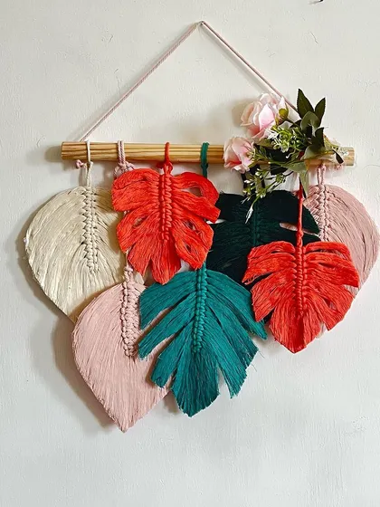 Bring the tropics indoors with this stunning monstera leaf wall hanging. The mix of vibrant red, teal, and soft pinks makes for a playful and stylish piece.