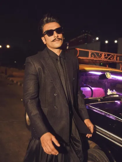 A close-up of Ranveer Singh, highlighting the details of the pinstripe suit and the sharp, confident attitude. The sunglasses add a final touch of star power.