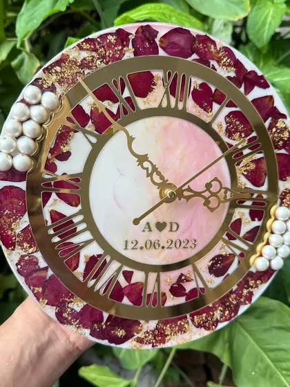 A 10-inch wedding clock featuring preserved red rose petals and a dual-tone pink and white center. The design includes the couple's initials and wedding date.