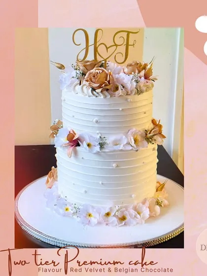 This two-tier premium wedding cake combines Red Velvet and Belgian Couverture Chocolate for a truly luxurious taste. The elegant white frosting and delicate floral arrangements make it a timeless choice for any wedding.