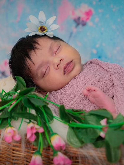 A slightly different angle of the sleeping baby girl in the floral basket setup. Her peaceful expression is just perfect.