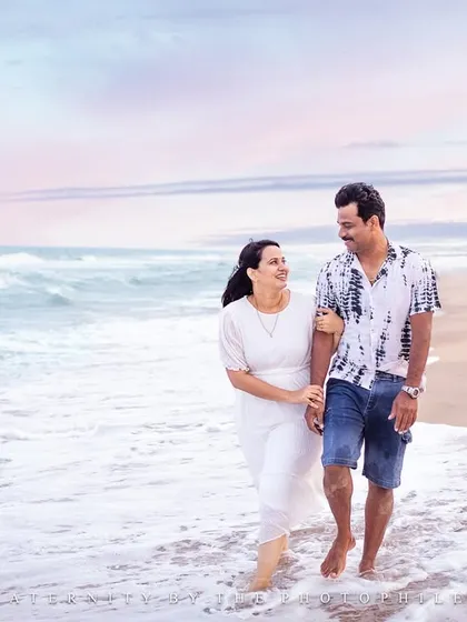 A quiet walk along the water's edge. This photo captures a moment of connection between a couple, with the gentle waves and soft light creating a romantic and serene atmosphere for their beach photoshoot.