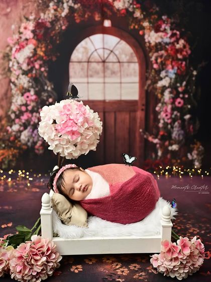 A sleeping beauty in a floral wonderland. This newborn is resting peacefully on a tiny bed, surrounded by a magical, glowing floral archway.