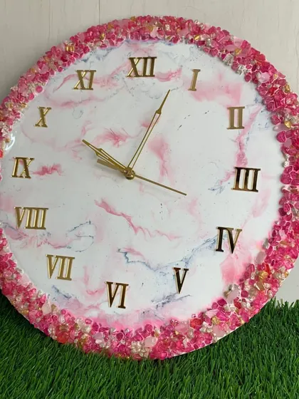 A vibrant pink marble clock with a full border of pink and gold crystals.