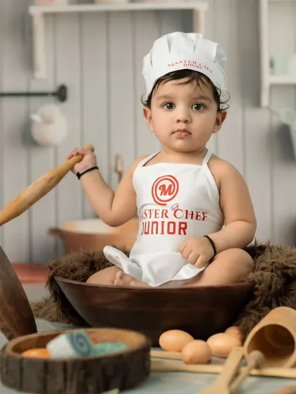 A portrait of our "Master Chef Junior" ready for culinary action. Themed shoots like this are perfect for sitter sessions, capturing a baby's steady posture and curious gaze.