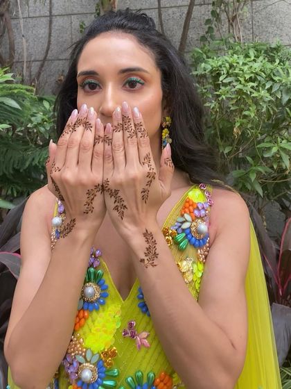 A close-up showing the bride's beautiful mehendi design. The makeup is kept clean to let the intricate details of her outfit and henna shine.