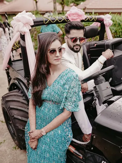 The couple strikes a pose in a decorated jeep, looking stylish and ready to celebrate.