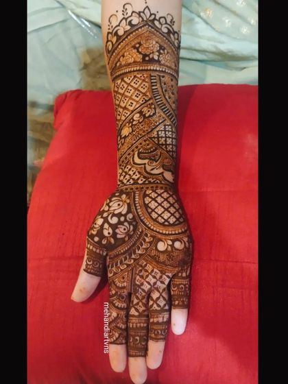 This design showcases a mix of different traditional patterns, including checks, swirls, and florals, creating a rich tapestry of henna art on the arm.
