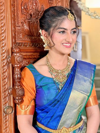 A youthful and fresh South Indian bridal look. The makeup is kept light and radiant to match her bright, joyful smile and the vibrant colors of her saree.
