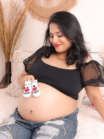 A sweet solo shot in a casual outfit, holding tiny baby booties over the bump. It’s a simple, heartfelt way to show love for the little one on the way.